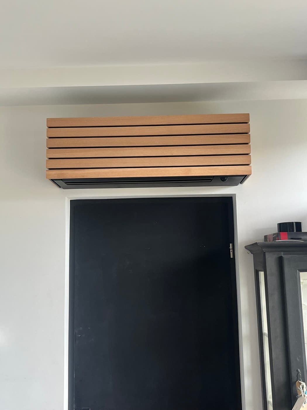 Close-up van de eikenhouten maatwerk-omkasting rond het airco-binnendeel