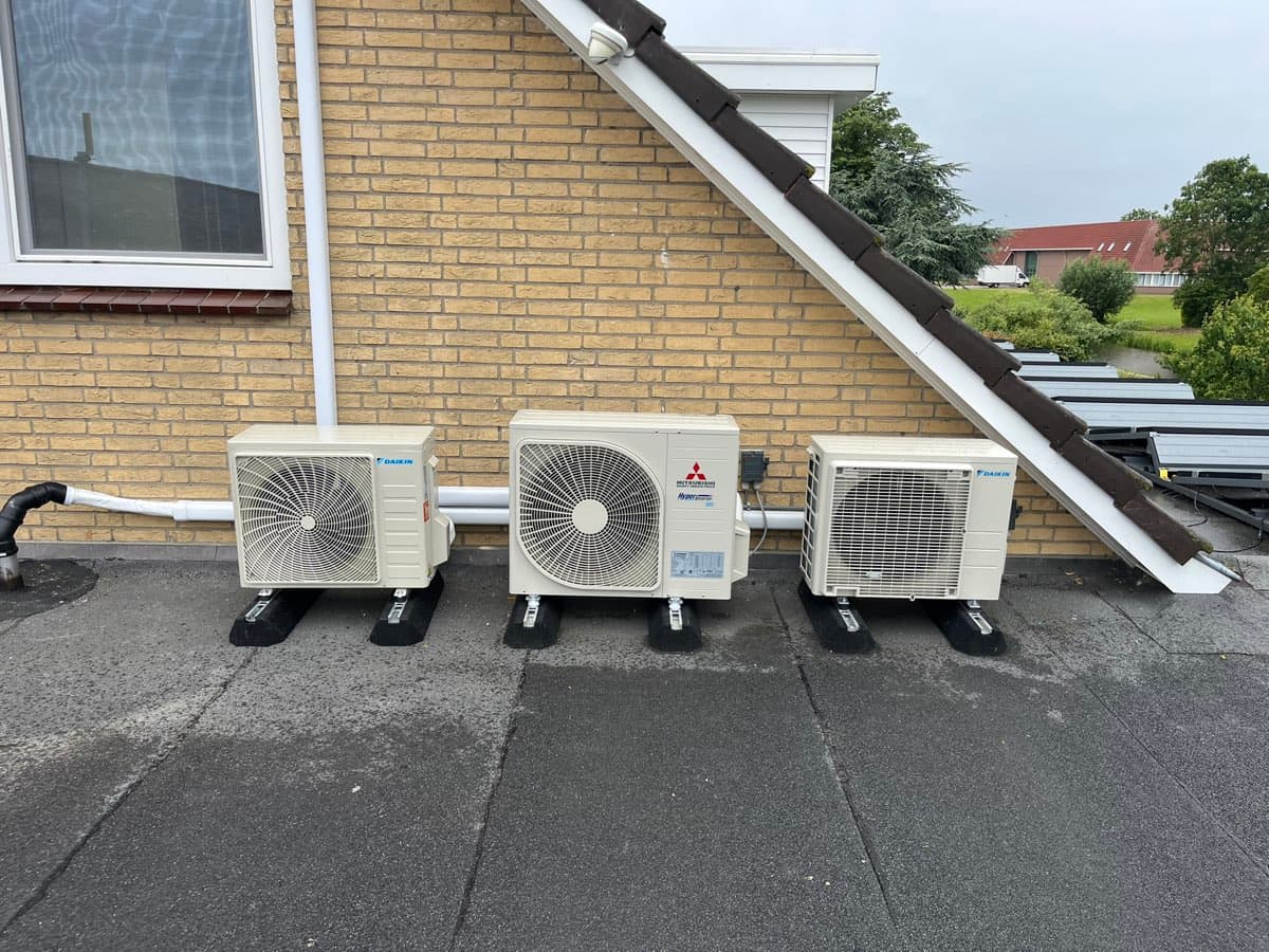 Drie airco-buitendelen van Daikin en Mitsubishi Heavy Industries op een rij op een plat dak