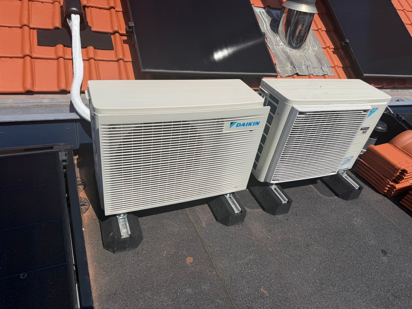 Twee Daikin-buitendelen op een plat dak naast zonnepanelen