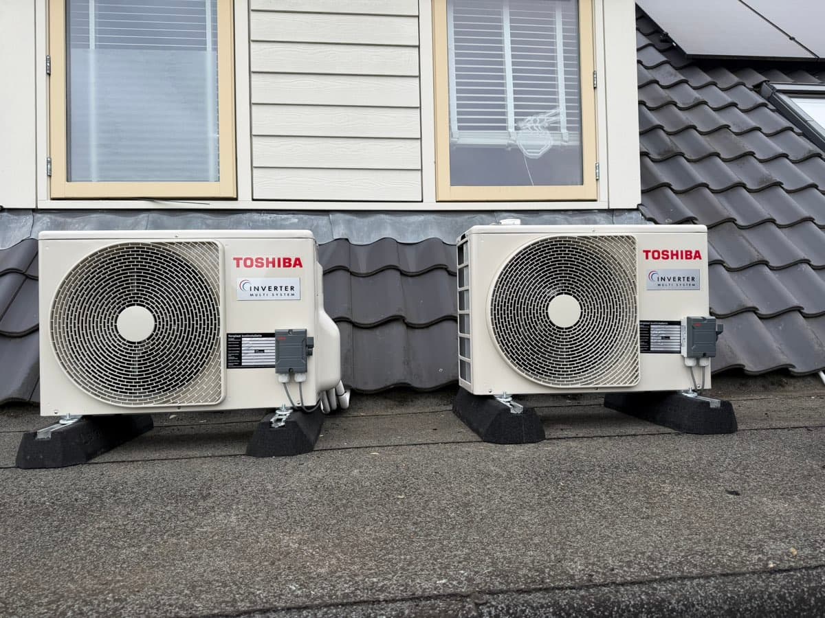Twee Toshiba-buitendelen naast elkaar op het platte dak van een dakkapel