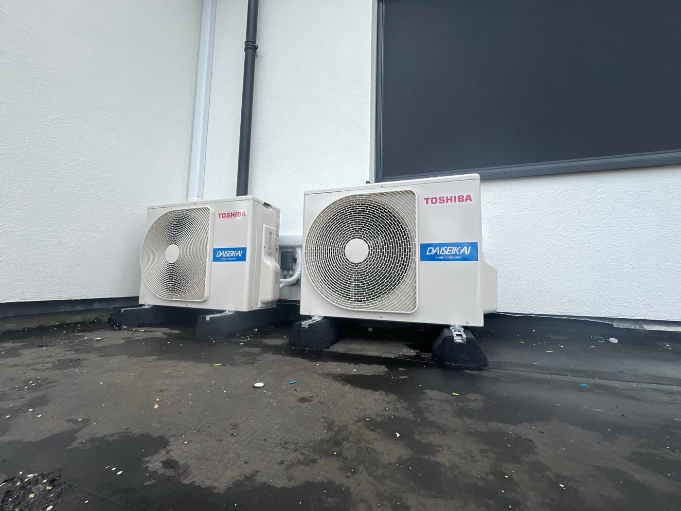 Twee Toshiba Daiseikai-buitendelen op rubberen dempers tegen een witte gevel