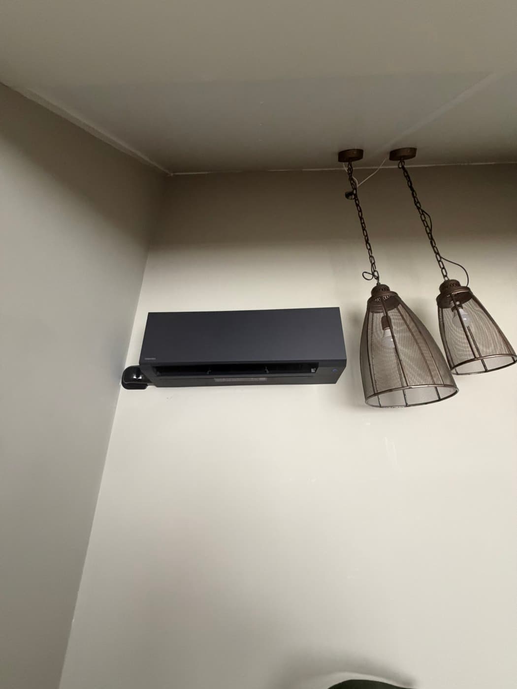 Matzwarte Toshiba-wandunit naast industriële hanglampen