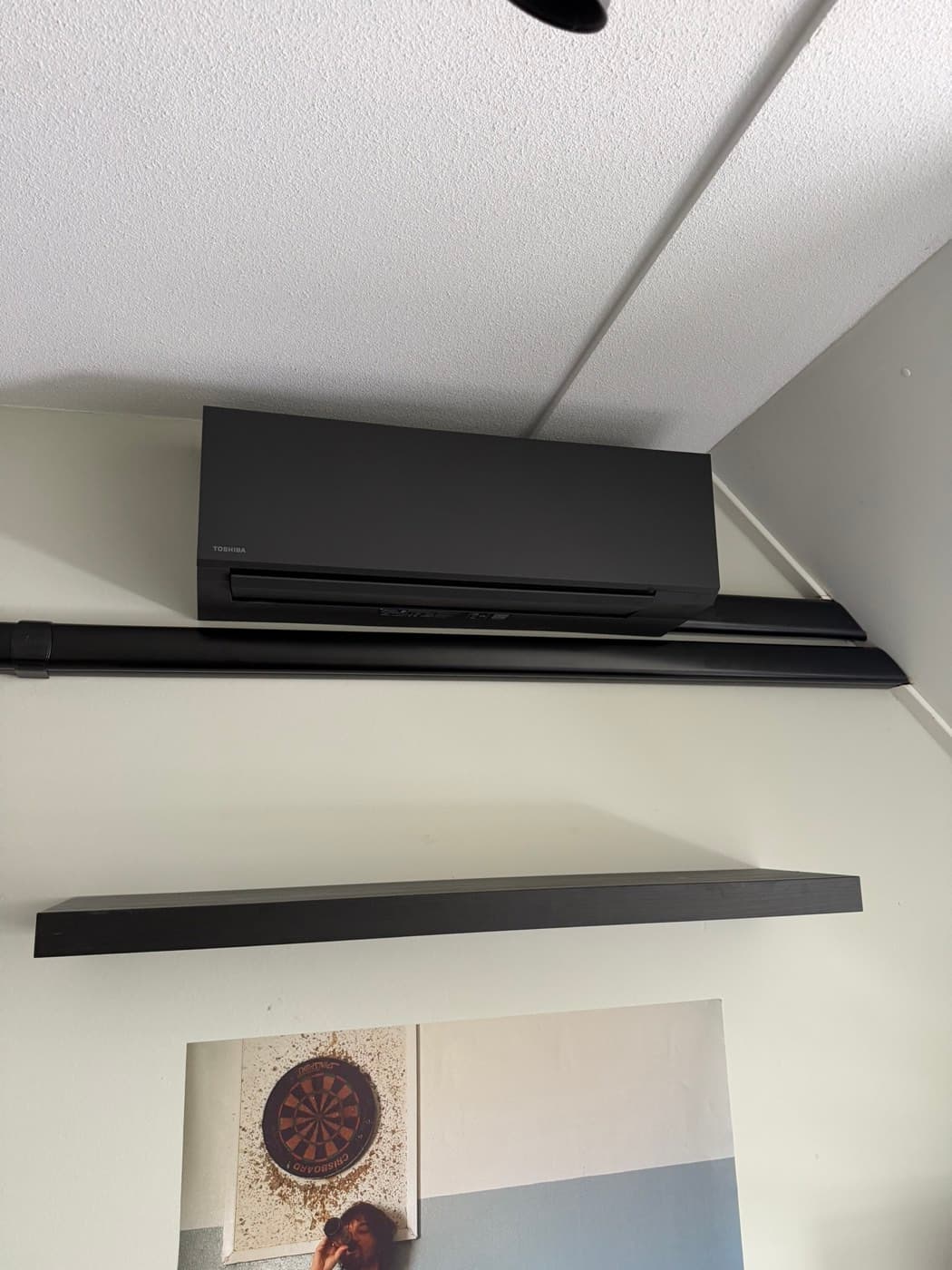 Matzwarte Toshiba-wandunit met zwarte leidinggoot op een zolderkamer