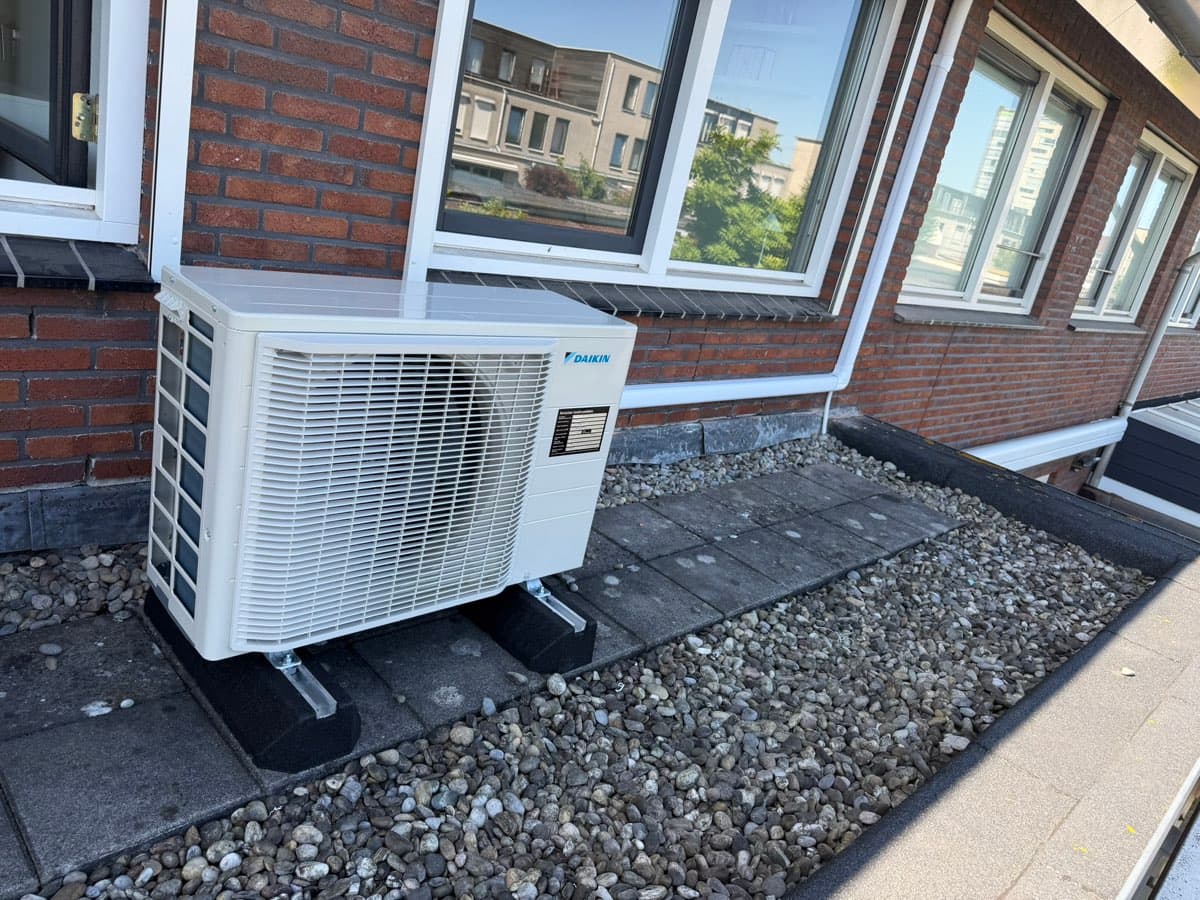 Daikin-buitendeel op een grinddak met nette leidinggoot